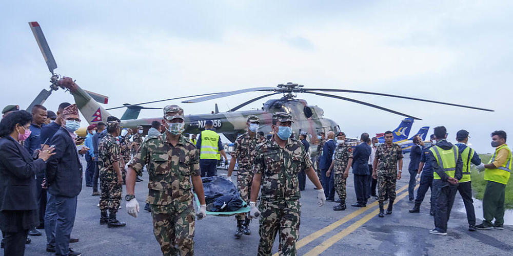 Nepalesische Armeeangehörige tragen die Leiche eines Opfers zu einem Krankenwagen am Flughafen in Kathmandu. Nach dem Absturz eines Passagierflugzeugs im Himalaya haben nepalesische Such- und Rettungskräfte 22 Todesopfer geborgen. Foto: Niranjan S...