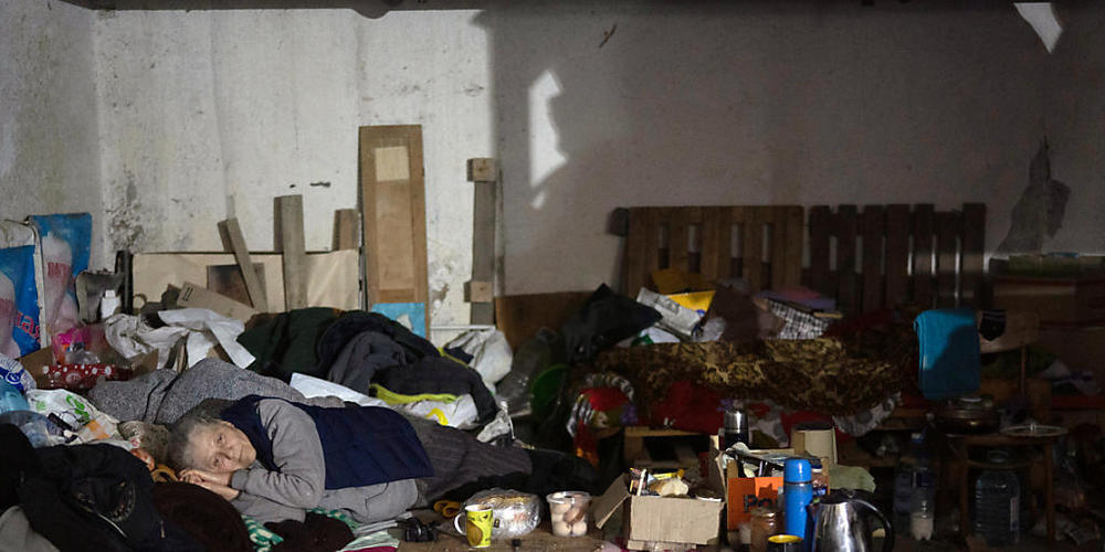 Eine alte Frau liegt auf einem Bett in einem Keller, der während russischer Angriffe auf Sjewjerodonezk als Luftschutzkeller genutzt wird. Foto: Leo Correa/AP/dpa