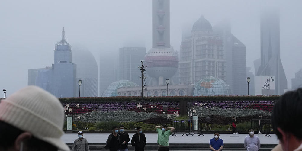 Menschen überqueren eine Straße. Nach zwei Monaten strengem Lockdown hebt Shanghai viele Corona-Beschränkungen auf. Seit Mittwoch durften die meisten der 26 Millionen Menschen ihre Wohnungen wieder verlassen. Foto: Ng Han Guan/AP/dpa