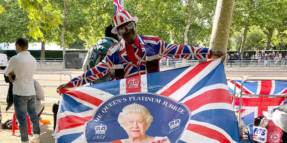 Joseph Afrane schwenkt eine Fahne mit einem Bild der Queen entlang der Pall Mall im Zentrum der Hauptstadt. Foto: Sophie Wingate/PA Wire/dpa