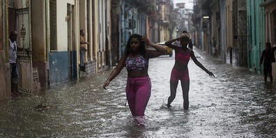 Zwei Frauen waten in Kubas Hauptstadt Havanna durch Hochwasser. Foto: Irene Perez/TheNEWS2 via ZUMA Press Wire/dpa