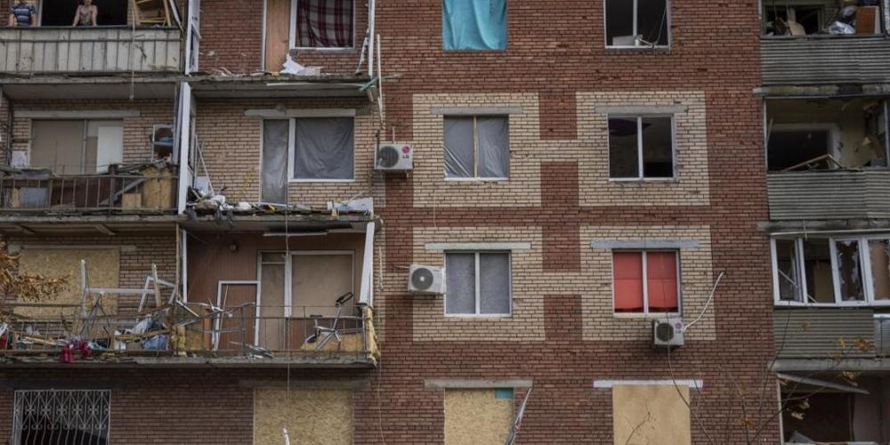 Eine Frau in Slowjansk schiebt einen Kinderwagen an einem durch russischen Beschuss beschädigten Gebäude vorbei. Foto: Bernat Armangue/AP/dpa