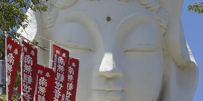 ARCHIV - Eine Frau spaziert mit Mundschutz und Sonnenschirm im japanischen Kamakura. Foto: Koji Sasahara/AP/dpa