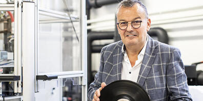 Musiker Philipp Fankhauser steht neben einer neuen Vinylpresse bei Adon in Neuenhof AG.