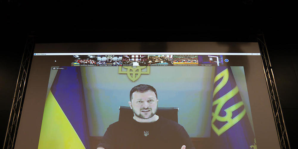 Wolodymyr Selenskyj (auf der Leinwand), Präsident der Ukraine, spricht per Video-Schalte zu Studenten der Universität Coventry. Foto: Jacob King/PA Wire/dpa