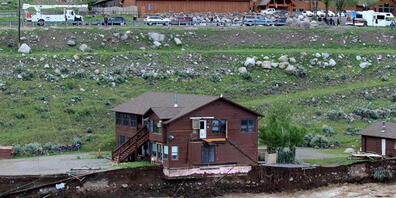HANDOUT - Der überflutete Yellowstone River unterspült das Ufer und gefährdet ein Haus und eine Garage. Foto: Sam Glotzbach/AP/dpa - ACHTUNG: Nur zur redaktionellen Verwendung bis zum 28.06.2022 im Zusammenhang mit der aktuellen Berichterstattung ...