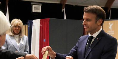Emmanuel Macron, Präsident von Frankreich, wirft seinen Stimmzettel in eine Wahlurne, während seine Frau Brigitte Macron daneben steht. Die Französinnen und Franzosen wählen ein neues Parlament. Foto: Michel Spingler/AP Pool/dpa