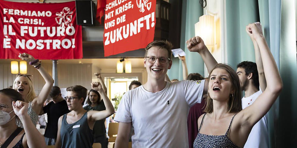 Der neu gewählte Juso-Präsident Nicola Siegrist, Mitte, singt mit der abtretenden Juso-Präsidentin Ronja Jansen "Die Internationale" an der Versammlung in Bern.