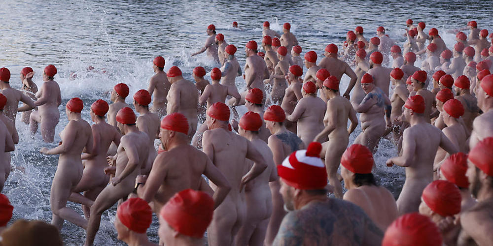Swimmers enter the water during the annual nude winter solstice swim during Hobart's Dark Mofo festival at Long Beach in Sandy Bay, Tasmania, Wednesday, June 22, 2022. (AAP Image/Rob Blakers) NO ARCHIVING