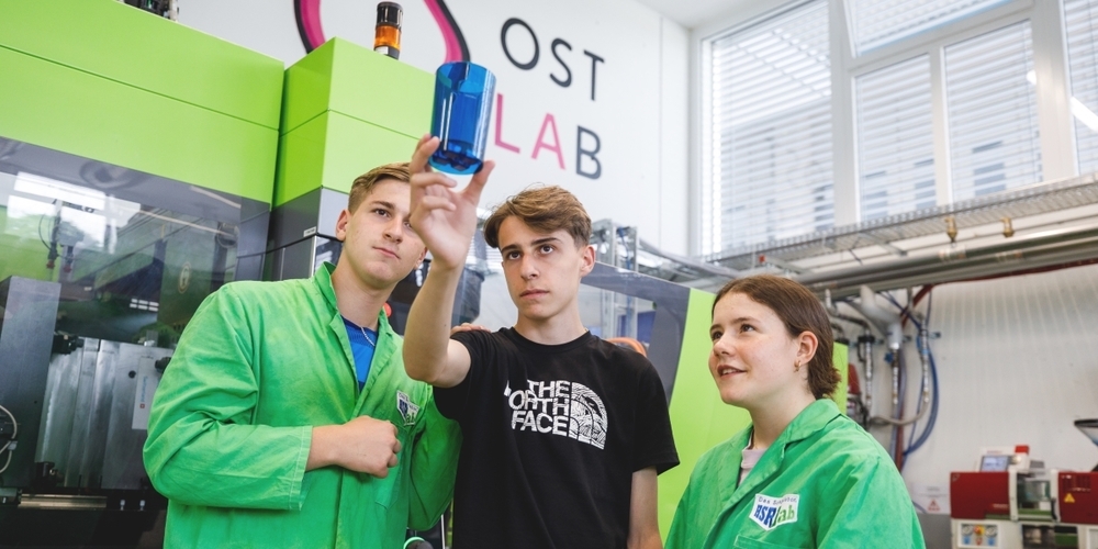 Eine Schülerin und zwei Schüler begutachten die selbstproduzierten Becher.
