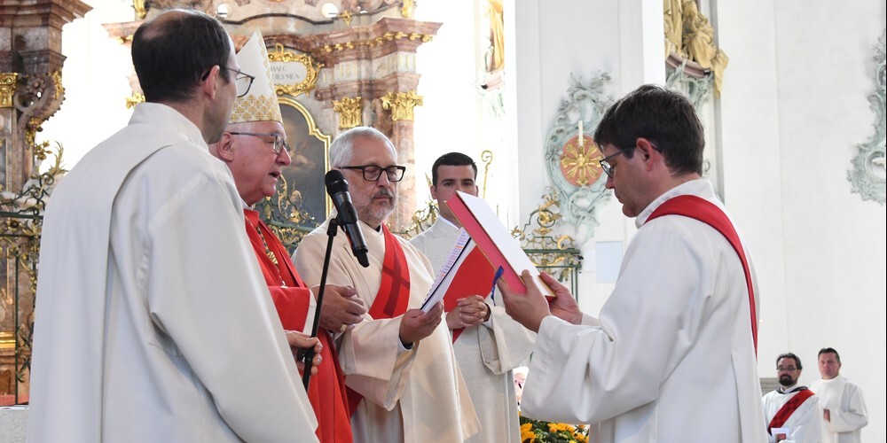 Bischof Markus Büchel übergibt Martin Rusch das Evangeliar.   