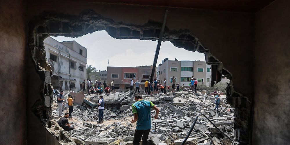 Palästinenser stehen nach einem israelischen Luftangriff in den Trümmern eines zerstörten Gebäudes in Gaza.
