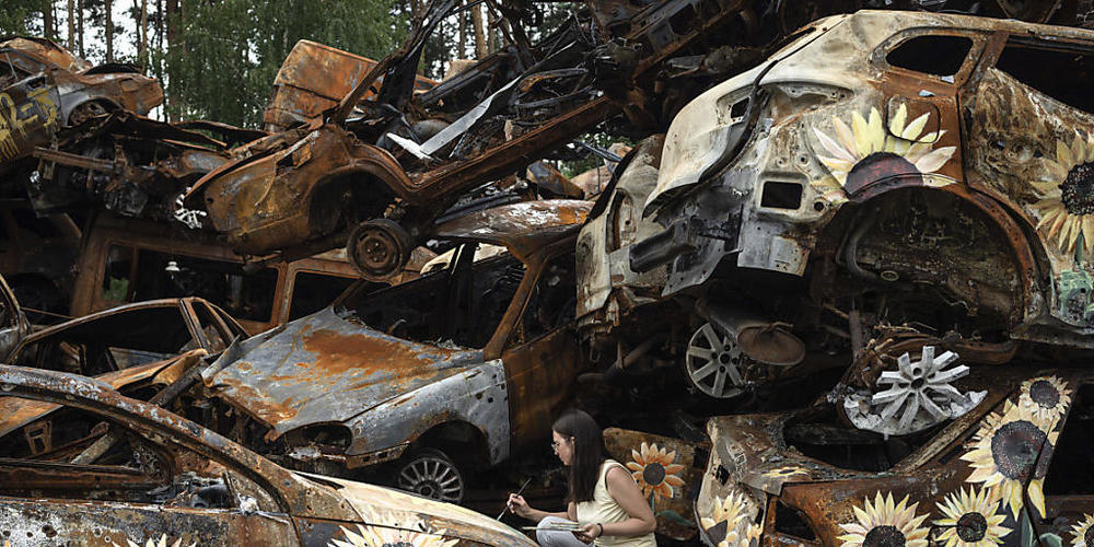dpatopbilder - Olena Yanko, Künstlerin aus der Ukraine, malt Sonnenblumen auf Autos, die durch russische Angriffe zerstört wurden. Foto: Evgeniy Maloletka/AP/dpa