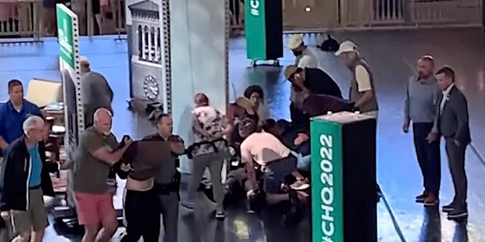 Dieses Videostandbild zeigt, wie ein Mann (l) von der Bühne eskortiert wird, während sich Menschen um den Autor Salman Rushdie in der Chautauqua Institution kümmern. Foto: Uncredited/AP/dpa