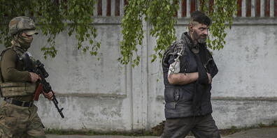 Ein russischer oder pro-russisch-separatistischer Soldat (links) führt einen Kämpfer des ukrainischen Asow-Regiments aus dem Stahlwerk in Mariupol ab. (Aufnahme vom 17. Mai 2022)