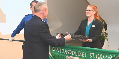 Kommandant Dr. Bruno Zanga überreicht einer Aspirantin (r.) die persönliche Dienstwaffe.