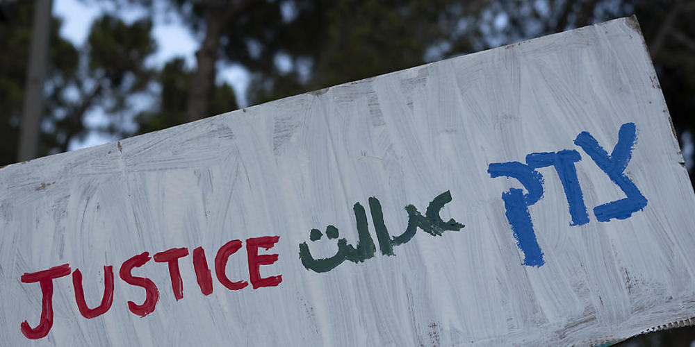 Eine israelische Frau hält ein Plakat mit der Aufschrift «Gerechtigkeit» in Englisch, Farsi und Hebräisch während einer Solidaritätskundgebung für Mahsa Amini. Foto: Maya Alleruzzo/AP/dpa