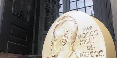 ARCHIV - Ein Aufsteller in Form der prestigeträchtigen Nobelmedaille weist vor dem Nobelpreismuseum in der Altstadt Gamla Stan auf die Tage der Nobelpreis-Bekanntgaben hin. Schwerwiegende Krisen scheinen in der diesjährigen Nobelpreis-Saison so om...