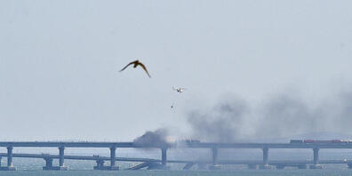 Ein Hubschrauber wirft Wasser ab, um das Feuer auf der Krim-Brücke zu stoppen, die das russische Festland und die Halbinsel Krim über die Straße von Kertsch verbindet. Foto: Uncredited/AP/dpa