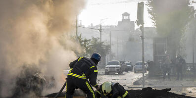 Ein Feuerwehrmann hilft seinem Kollegen aus einem mit Wasser gefüllten Krater, während sie ein brennendes Auto löschen. Nach russischen Raketenangriffen ist der Luftalarm in der ukrainischen Hauptstadt Kiew nach mehr als fünfeinhalb Stunden aufgeh...