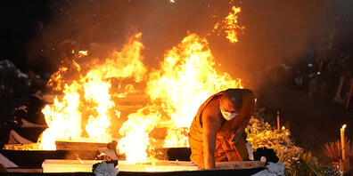 Ein Mönch zündet im Wat Rat Samakee Tempel die Einäscherungsstätten der Opfer der Schüsse in einer Kindertagesstätte an. Foto: Sakchai Lalit/AP/dpa