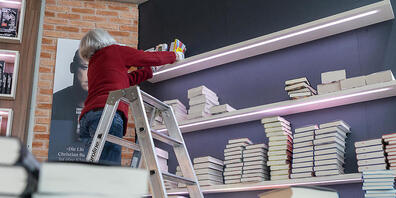 Eine Frau räumt vor der Eröffnung der Frankfurter Buchmesse Bücher ein. Foto: Sebastian Christoph Gollnow/dpa