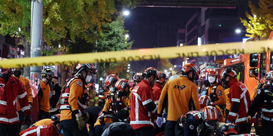 dpatopbilder - Rettungskräfte und Feuerwehrleute sind an der Unfallstelle im Einsatz. Dutzende Personen haben beim Ansturm auf Halloween-Feierlichkeiten in Seoul einen Herzstillstand erlitten. Foto: Lee Ji-Eun/Yonhap/AP/dpa