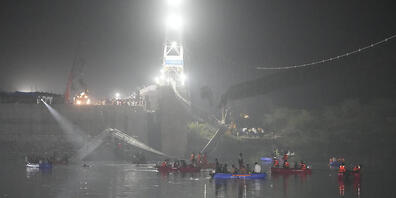 dpatopbilder - Retter auf Booten suchen im Fluss Machchu neben einer eingestürzten Kabelbrücke in der Stadt Morbi im westlichen Bundesstaat Gujarat, Indien. Foto: Ajit Solanki/AP/dpa