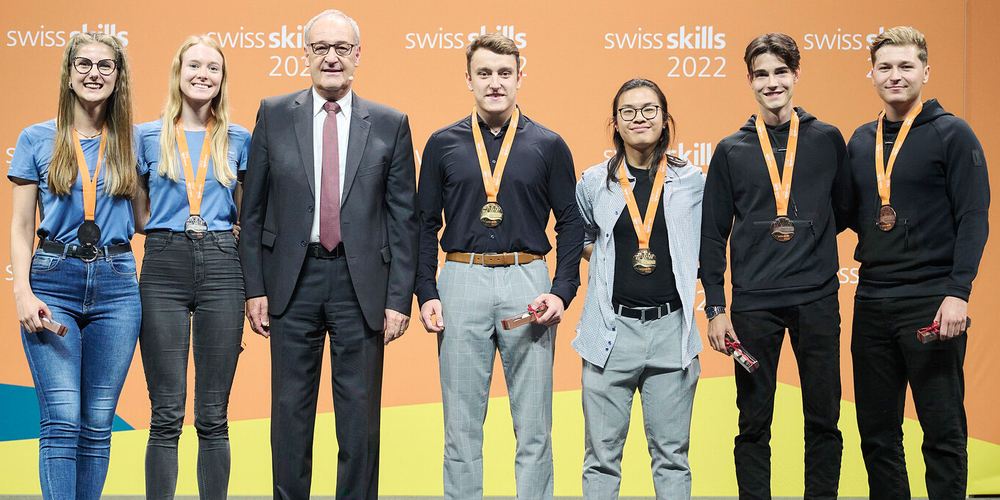 Maria Näf und Julia Koch neben Bundesrat Guy Permelin sowie den Erst- und Drittplatzierten (v.l.) der SwissSkills 2022 in der Disziplin «Entrepreneurship»