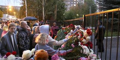 Nach den Schüssen in der Schule Nummer 88 legen Menschen Blumen und Spielzeug nieder und zünden Kerzen an. Foto: Sergei Kuztsov/AP/dpa