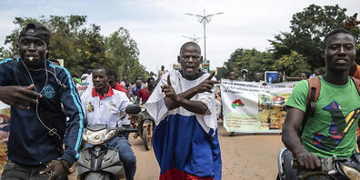 Ein in eine russische Fahne gehüllter Mann ruft bei einem Prtest in Ouagadoudou Slogans gegen die Macht von Oberstleutnant Damiba und gegen Frankreich. Foto: Sophie Garcia/AP/dpa