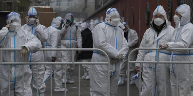 Arbeiter in Schutzanzügen in einem abgesperrten Viertel. Foto: Andy Wong/AP/dpa