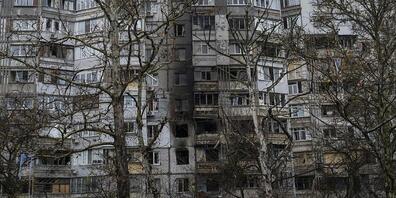 Eine Frau geht in Cherson an einem kürzlich durch einen Angriff beschädigten Gebäude vorbei. Foto: Bernat Armangue/AP/dpa