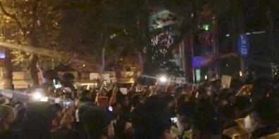 SCREENSHOT - In diesem Bild aus einem Video, das The Associated Press erhalten hat, beobachtet die Polizei (im Vordergrund) die Demonstranten in Shanghai. Foto: Uncredited/AP/dpa