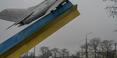 Autos fahren an der Skulptur eines Flugzeugs vorbei, während sie Cherson verlassen. Foto: Bernat Armangue/AP/dpa