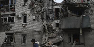 Eine Frau geht nach einem russischen Luftangriff in Tschassiw Jar an den Trümmern eines zerstörten Hauses vorbei. Foto: Andriy Andriyenko/AP/dpa