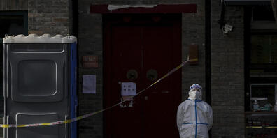 dpatopbilder - Ein Arbeiter in Schutzkleidung steht in Peking Wache in einem abgesperrten Viertel. Foto: Andy Wong/AP/dpa