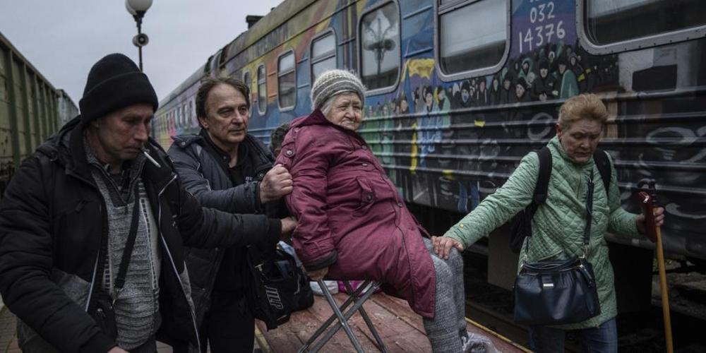 Angehörige einer älteren Frau transportieren sie zu einem Evakuierungszug in Cherson. Foto: Evgeniy Maloletka/AP/dpa