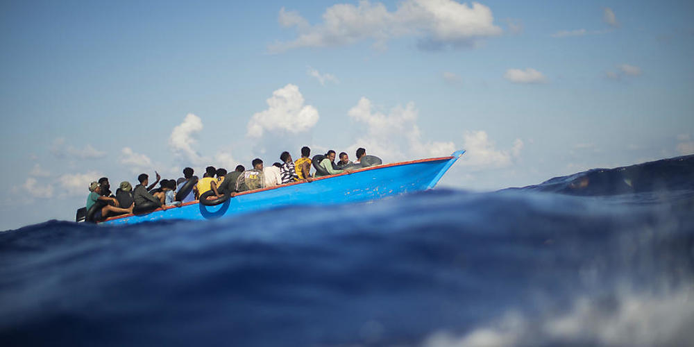 ARCHIV - Migranten sitzen in einem Holzboot südlich der italienischen Insel Lampedusa auf dem Mittelmeer. Foto: Francisco Seco/AP/dpa