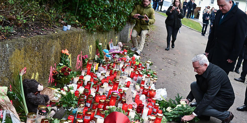 Thomas Strobl (kniend, CDU), Innenminister von Baden-Württemberg, und Ahmet Basar Sen (r), Botschafter der Türkei in Deutschland, legen am Tatort eines Messerangriffs auf zwei Mädchen bei einer Schweigeminute einen Kranz nieder. Foto: Bernd Weißbr...