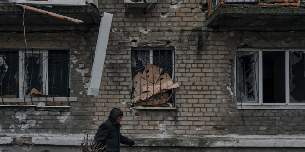 Ein Mann trägt Reisig für einen Holzofen zum Keller eines Wohnhauses, der als Bunker genutzt wird. Foto: Libkos/AP/dpa