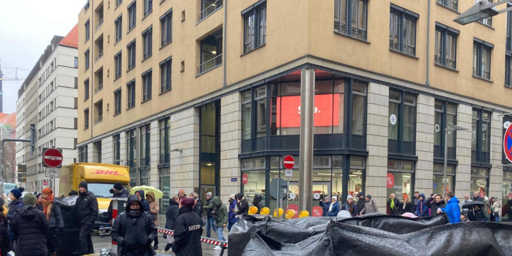 Menschen und Mitarbeiter eines Sicherheitsunternehmens stehen in der Nähe der Altmarktgalerie nach einer Geiselnahme. Foto: Jörg Schurig/dpa-Zentralbild/dpa