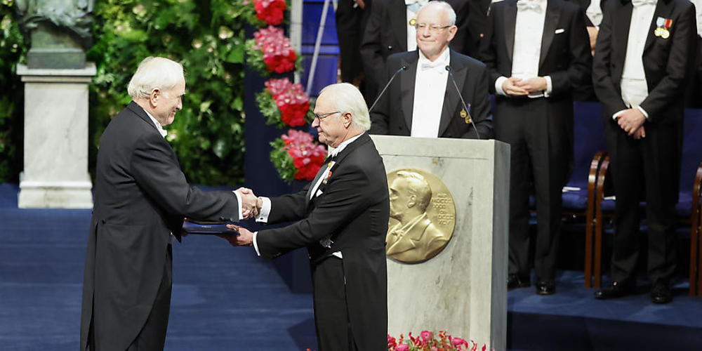 König Carl XVI. Gustaf von Schweden (r) übergibt John F. Clauser, Physiker aus den USA, den Nobelpreis für Physik während der Nobelpreisverleihung in der Konzerthalle. Foto: Christine Olsson/TT NEWS AGENCY/AP/dpa