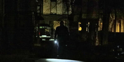 Ein Mann leuchtet sich den Weg mit einer Taschenlampe in einer dunklen Straße. Foto: --/Ukrinform/dpa