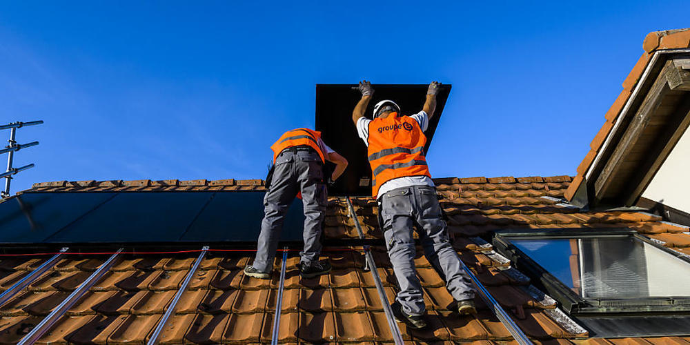 Arbeiter installieren eine Photovoltaik-Anlage im Kanton Freiburg. (Archivbild)