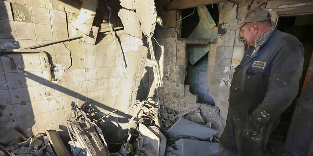 Ein Mann untersucht ein durch Beschuss beschädigtes Wohnhaus. Foto: Alexei Alexandrov/AP/dpa