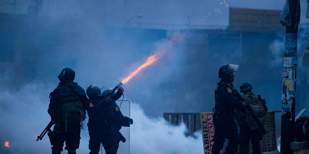 Ein Polizist feuert Tränengas in Richtung Demonstranten während eines Protests. Foto: Denis Mayhua/dpa