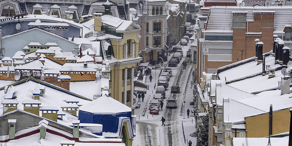Menschen gehen auf einer verschneiten Straße im Stadtzentrum von Kiew. Foto: Evgeniy Maloletka/AP/dpa