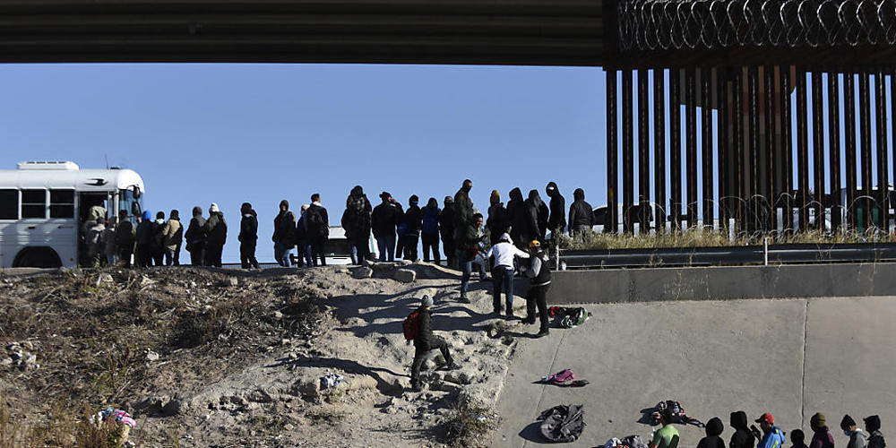 ARCHIV - Migranten warten auf den Einstieg in einen Bus der US-Regierung, nachdem sie die Grenze von Ciudad Juarez nach El Paso überquert haben. Foto: Christian Chavez/AP/dpa