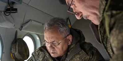 HANDOUT - Auf diesem vom Pressedienst des russischen Verteidigungsministeriums veröffentlichten Handout-Foto sieht sich Sergej Schoigu (l), Verteidigungsminister von Russland, an Bord eines Militärhubschraubers an einem ungenannten Ort in der Ukra...